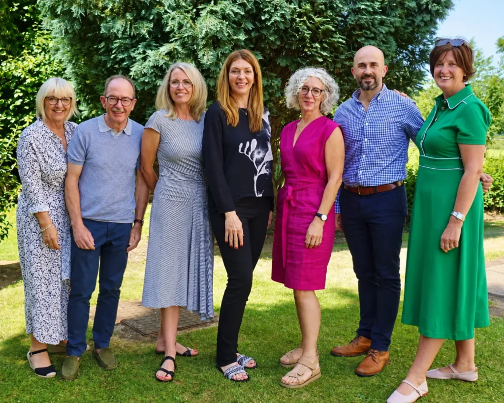 Seven members of the Age UK project team standing together outdoors in a garden.