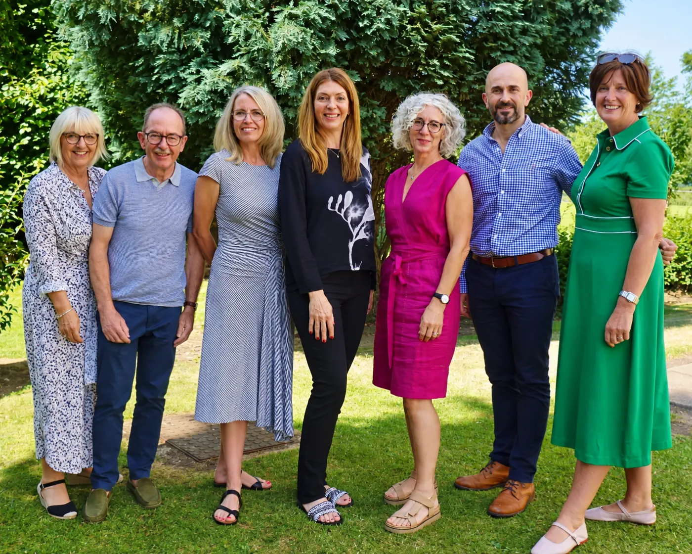 Seven members of the Age UK project team standing together outdoors in a garden.