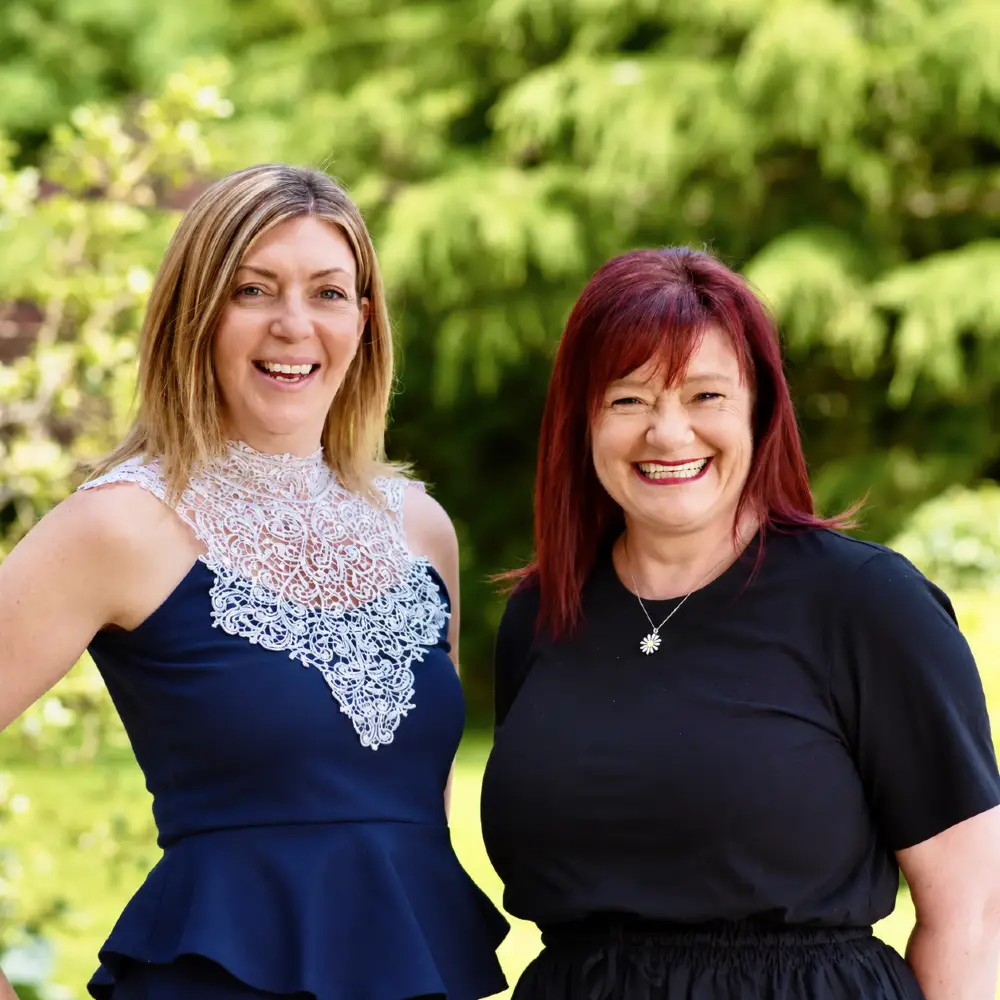 Two members of the Age UK project team smiling together outdoors.