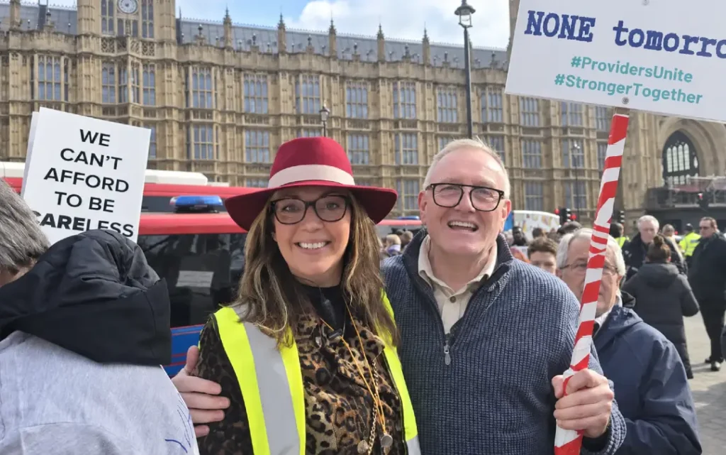 Providers Unite campaign participants outside the Houses of Parliament during a Westminster rally, with campaign placards visible.